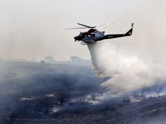 A helicopter attacks a wildfire burning in the north county of San Diego on Tuesday.AP