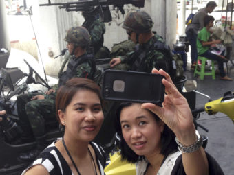 Residents stop to take a photo of themselves at a military checkpoint in central Bangkok on Tuesday. Thailand's army declared martial law in a surprise move it says is aimed at quelling political unrest. Kiko Rosario/AP
