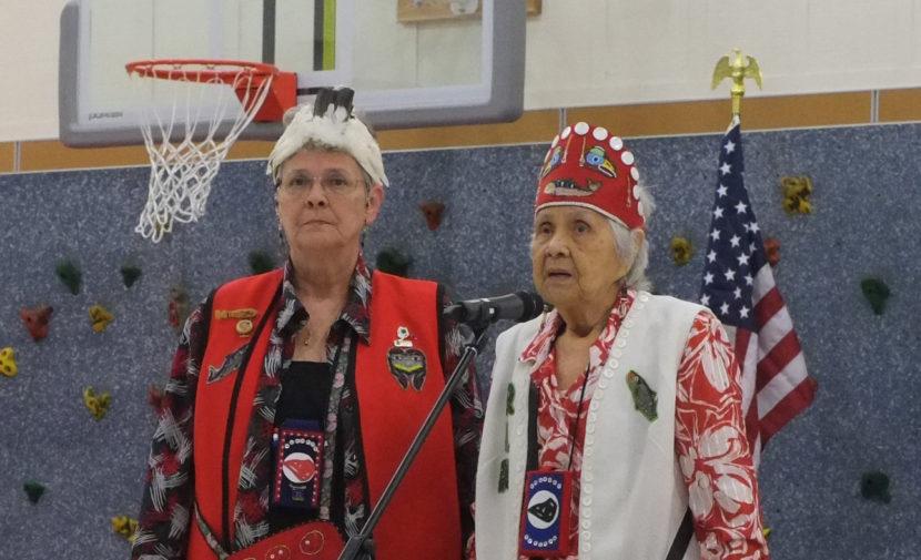 Two Tlingit women stand at microphone