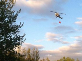 A helicopter drops water on the fire near Soldotna Monday night (Photo by Ariel Van Cleave)