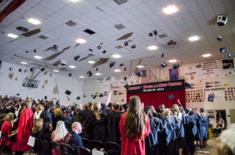 Graduates throw their caps into the air after receiving their diplomas. Rap music played as the students left the gym. (Photo by Heather Bryant/KTOO)