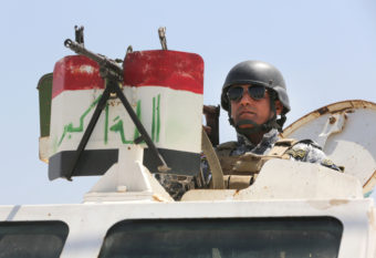 An Iraqi federal policeman standing on top an armored vehicle secures a checkpoint in Baghdad, Iraq, on Sunday. Karim Kadim/AP
