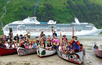 The paddlers pose as a cruise ship goes by Sandy Beach. (Photo by Ed Schoenfeld/CoastAlaska News)