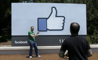 A man poses for photographs in front of the Facebook sign on the Facebook campus in Menlo Park, Calif. Jeff Chiu/AP