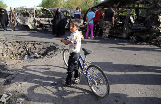 An Iraqi boy and other civilians look at the aftermath of a car bomb in Baghdad's Sadr City on Wednesday. The violence in the Shiite district comes as Sunni militants advance in northern Iraq. Karim Kadim/AP