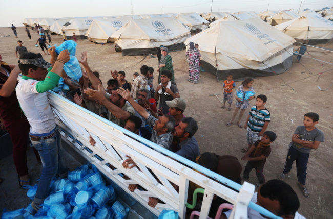 Displaced Iraqi citizens receive meals to break their Ramadan fast from a Kurdish charity group. Iraq's central government has launched its first major operation against the ISIS insurgent group. Hussein Malla/AP
