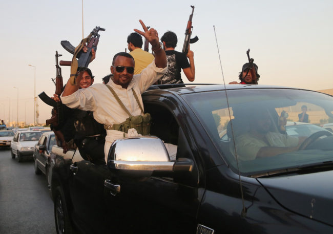 Shiite tribal fighters raise their weapons and chant slogans against the al-Qaida-inspired Islamic State of Iraq and Syria (ISIS) in Basra on Sunday. Nabil Al-Jurani/AP