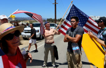 Miguel Hernandez (right), an immigrant rights activist, stands among anti-immigration activists outside of the U.S. Border Patrol's Murrieta station on Monday. The federal agency says it will not fly more detained migrants to be processed at the facility. Sandy Huffaker/Getty Images