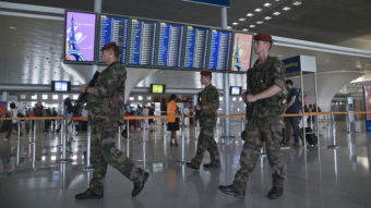 In Paris, soldiers patrol at Charles de Gaulle airport last week. French airports have reportedly agreed to a new TSA policy requiring electronic devices to be powered up before they're allowed on U.S.-bound flights. Michel Euler/AP