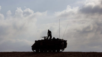 An Israeli soldier stands on a military vehicle near Gaza early Tuesday, when a cease-fire was meant to take effect. The deal hasn't been embraced by all of Hamas. Ariel Schalit/AP