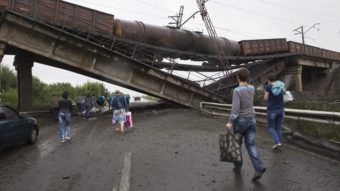 People walk under a destroyed railroad bridge over a main road leading into the city of Donetsk in eastern Ukraine Monday. Kiev is calling on pro-Russian militants to disarm before holding peace talks. Dmitry Lovetsky/AP