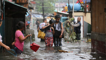 Residents wade through floods as they go back to their home while Typhoon Rammasun batters suburban Quezon city, north of Manila, on Wednesday. Aaron Favila/AP