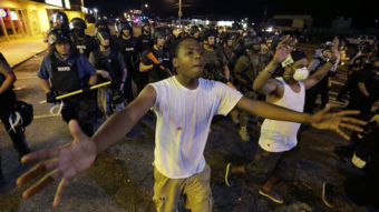 Protesters walk in front of a line of police as authorities try to disperse a demonstration in Ferguson, Mo. early Wednesday. The St. Louis suburb saw less violence than recent nights of protests. Charlie Riedel/AP