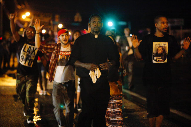 A clergyman leads demonstrators protesting the shooting death of Michael Brown down West Florissant Avenue in Ferguson, Mo., on Wednesday. A large contingent of clergy helped keep the mood calm after days of unrest. Eric Kayne for NPR