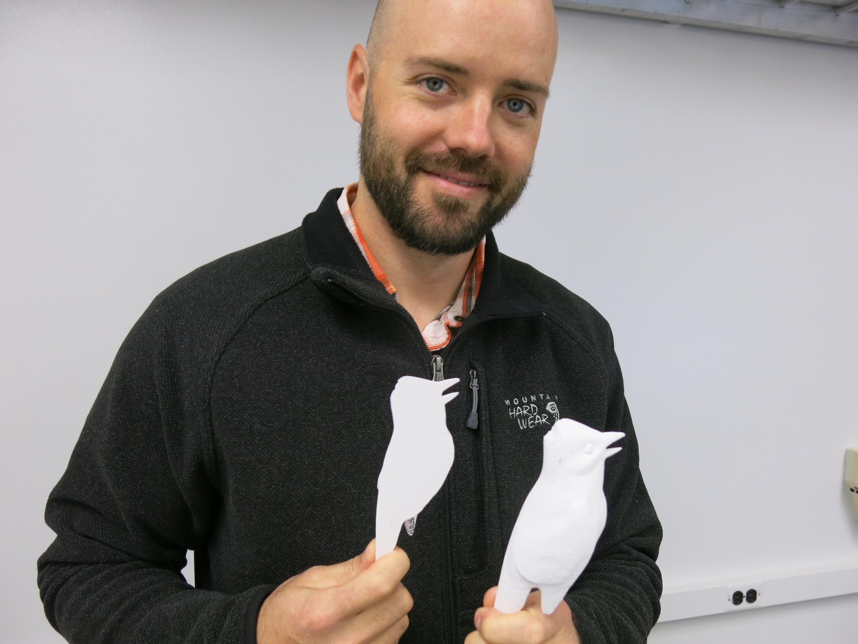 Designer Andy Cummins with two halves of a songbird decoy produced on a 3-D printer. (Photo by Ned Rozell)