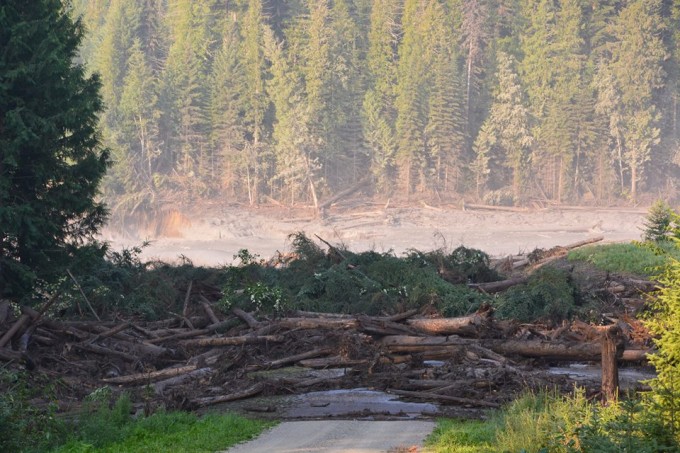 Muddy water from the breached Mount Polley Mine tailings pond dam floods a downstream creek and road Monday. Fishing and environmental groups say the same could happen at new B.C. mines near the Southeast border. (Cariboo Regional District Emergency Operations Centre photo)