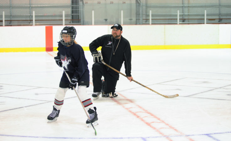 Rocky Mountain Hockey School coach Zac Desjardins watches over Taylor Bentley as she’s about to receive a pass then relay it to another player during a Rocky Mountain High School drill at Treadwell Ice Arena.