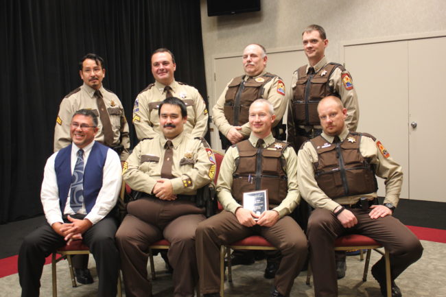 Tlingit-Haida Central Council's VPSO coordinator Jason Wilson (bottom row, left) sits with the seven VPSOs serving Southeast Alaska after a ceremony held in Juneau Monday. VPSO of the Year Zach West holds his award. (Photo by Lisa Phu/KTOO)