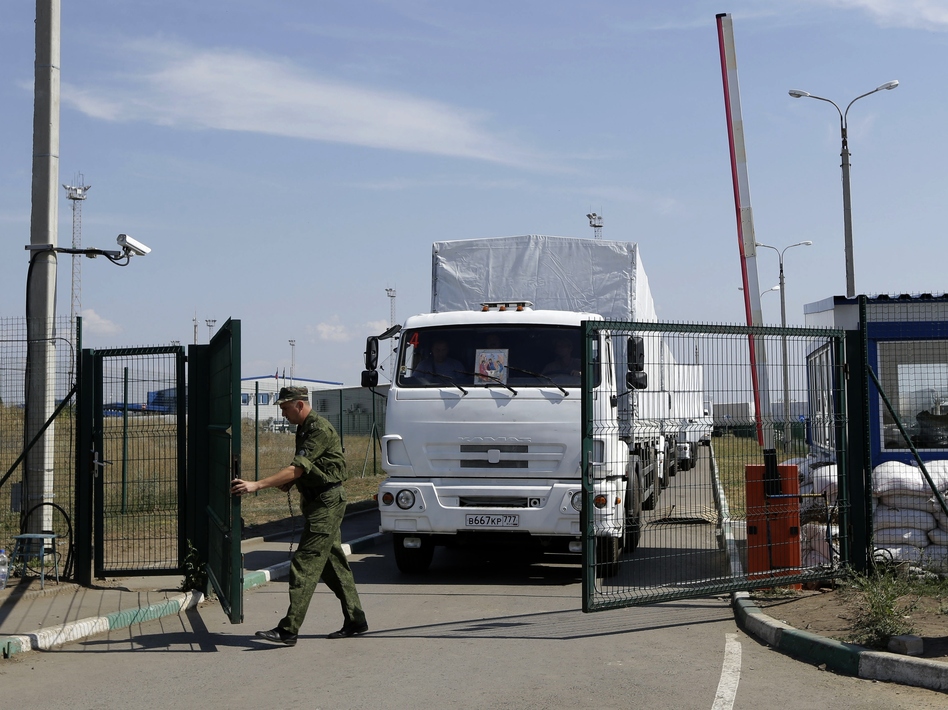 A Russian border guard opens a gate into the Ukraine for the first trucks from the Russian town of Donetsk, Rostov-on-Don region, on Friday. The convoy had been stalled near the border for more than a week. Sergei Grits/AP