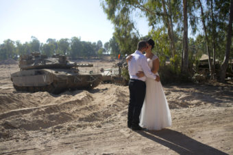 An Israeli couple, Noga and Moshiko Siho, kiss after they have their wedding photos taken Wednesday in an army staging area on the Israel-Gaza border, near Kibbutz Yad Mordechai, Israel. Oded Balilty/AP
