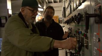 Walt Dangle, former Sitka Electric Department operator, and Frank Rogers, Senior Power Plant Operator shut down the Blue Lake hydroelectric powerhouse. (Photo courtesy Blue Lake Expansion/YouTube)