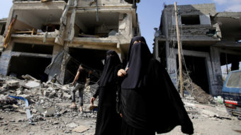 Palestinian women walk past the rubble of their homes in Gaza City's Shijaiyah neighborhood on Monday. An Egyptian-brokered cease-fire halting the Gaza war held into Monday morning, allowing Palestinians to leave homes and shelters as negotiators agreed to resume talks in Cairo. Hatem Moussa/AP