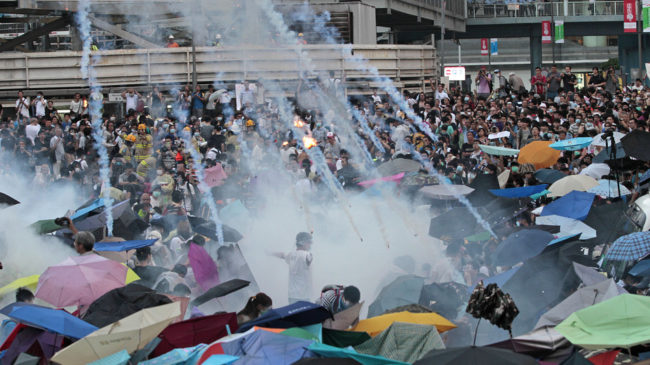 Riot police launch tear gas into a crowd of thousands of protesters outside the government headquarters in Hong Kong Sunday. Police warned of further measures as they tried to clear the streets. Wally Santana/AP