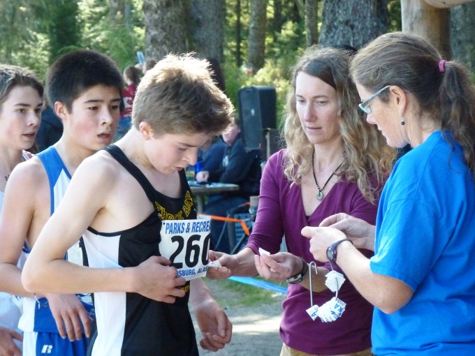 Volunteers remove digital timing tags from races' bibs at the end of Saturday's boys' race. (Ed Schoenfeld, CoastAlaska News)