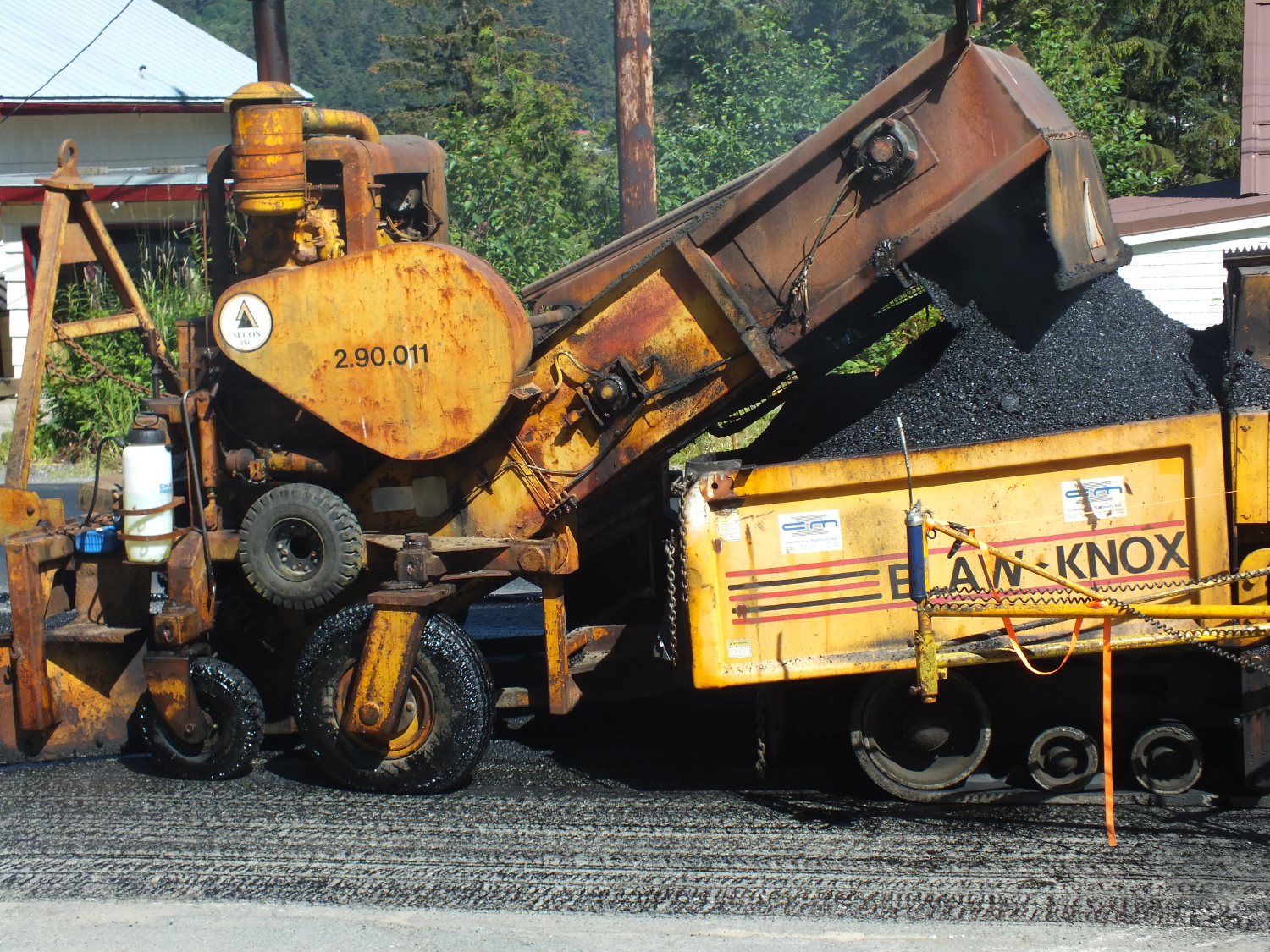 Asphalt is scooped up and fed into spreader. (Photo by Matt Miller/KTOO)