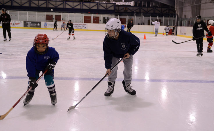Cully Corrigan skates the length of the rink with Tyler Frisby during a Learn to Play afternoon sponsored by the Juneau Douglas Ice Association and Treadwell Ice Arena.