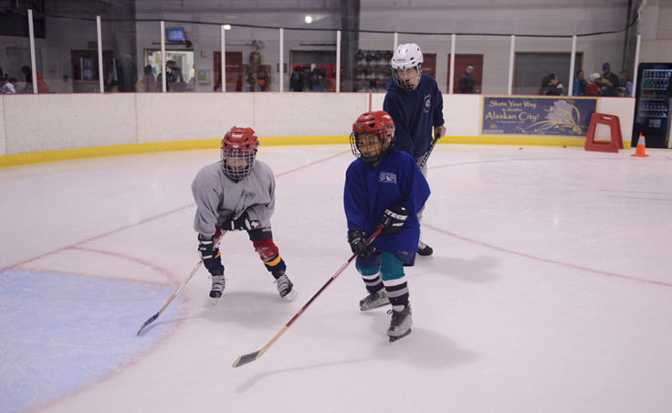 Cully Corrigan looks on as Emma Jessen and Tyler Frisby compete for an incoming puck in front of the net during a Learn to Play afternoon sponsored by the Juneau Douglas Ice Association and Treadwell Ice Arena.