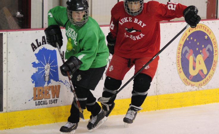 Suzanne McGee (left) and Griffin McKinney battle for the puck while coming round the net and along the boards.
