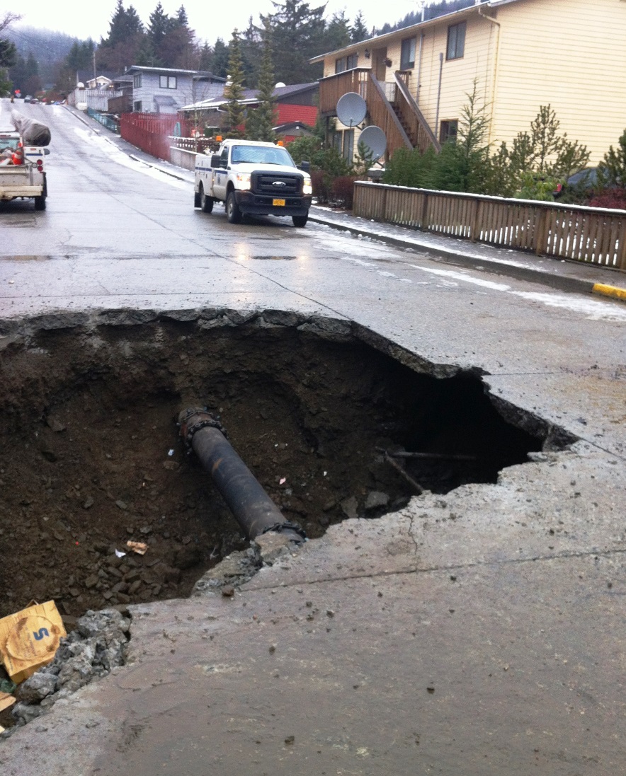 A large hole surrounds a repaired Ketchikan water-main break in December, 2013. The fill dirt under the street was washed away. Water and sewer line repairs are on the city's ballot.
