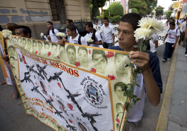 Students hold a banner with the faces of the missing that reads in Spanish "Iguala, cradle of murders." Eduardo Verdugo/AP