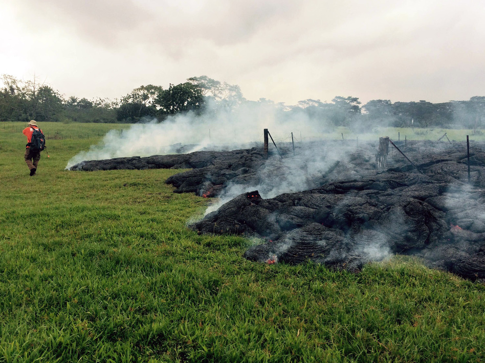A geologist maps the margin of the lava flow in the open field below Cemetery Road near the town of Pahoa on the Big Island of Hawaii. Dozens of residents from the village may be forced to evacuate. AP 