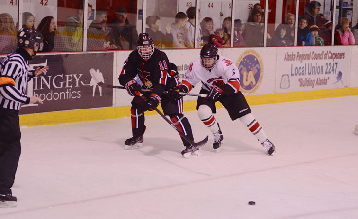 Juneau’s Quin Gist battles Kenai’s Riley Weber in the corner for the puck in Friday night’s game versus Kenai.