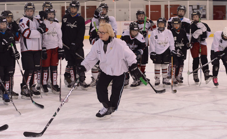 Laura Stamm demonstrates proper form in crossing one stake over another and efficiently pushing off each stride before a group of Juneau youth hockey players at Treadwell Ice Arena.