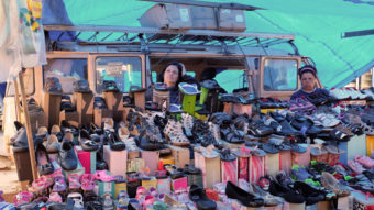 A woman waits for customers at a street market where she sells shoes in Sao Paulo. Brazil and other Latin American economies have prospered by selling commodities and low-tech goods. But now many economies are struggling, and some point to the region's lack of high-tech and other cutting-edge industries. (Photo by Andre Penner/AP)
