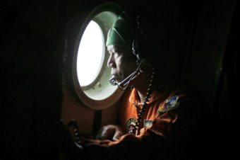 A crew of an Indonesian Air Force C-130 airplane of the 31st Air Squadron looks out of the window during a search operation for the missing AirAsia flight 8501 jetliner over the waters of Karimata Strait in Indonesia, on Monday. Dita Alangkara/AP