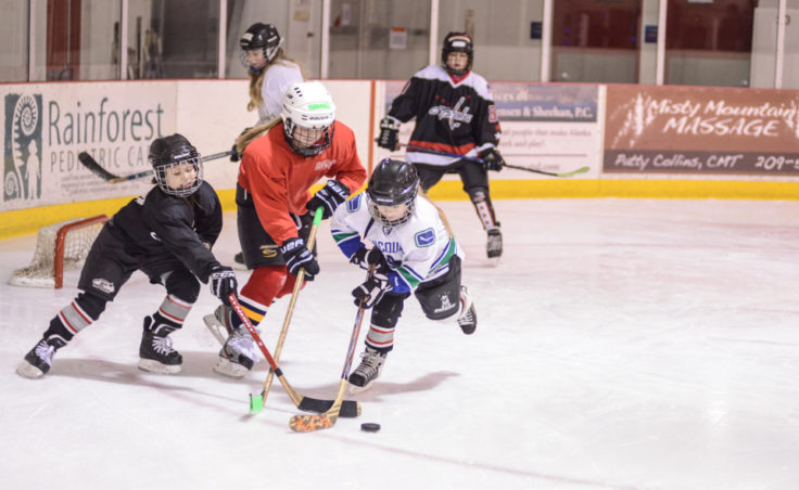 Ema Jessen (left), Cara Wesley and Rayanna Wolfenberger battle for the puck during the all-girls clinic at Treadwell Ice Arena.