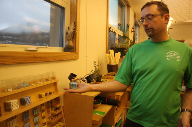 Montessori Borealis teacher Cory Crosset explains how the bead chain cabinet shows mathematical concepts in physical form rather than on a piece of paper. (Photo by Lisa Phu/KTOO)