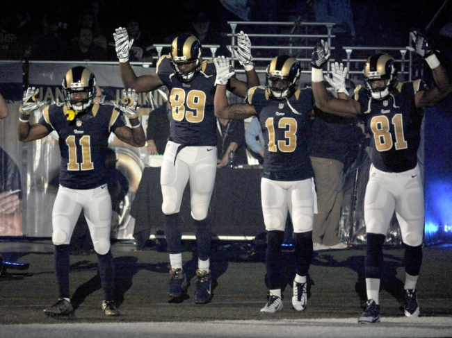 Members of the St. Louis Rams raise their arms in a "hands up, don't shoot" pose as they walk onto the field before an NFL football game against the Oakland Raiders. (Photo by L.G. Patterson/AP)