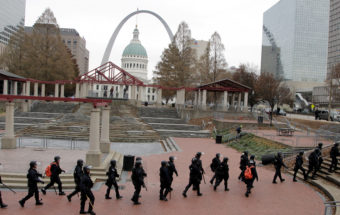Officers wearing riot gear walk through a park in downtown St. Louis on Sunday. (Photo by Tom Gannam/AP)