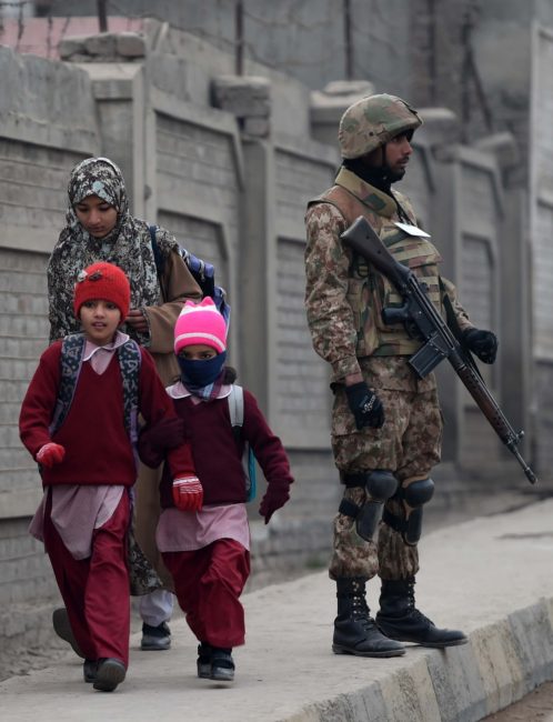 A Pakistani soldier stands guard on a street as children walk to school in Peshawar on Monday. A Majeed /AFP/Getty Images