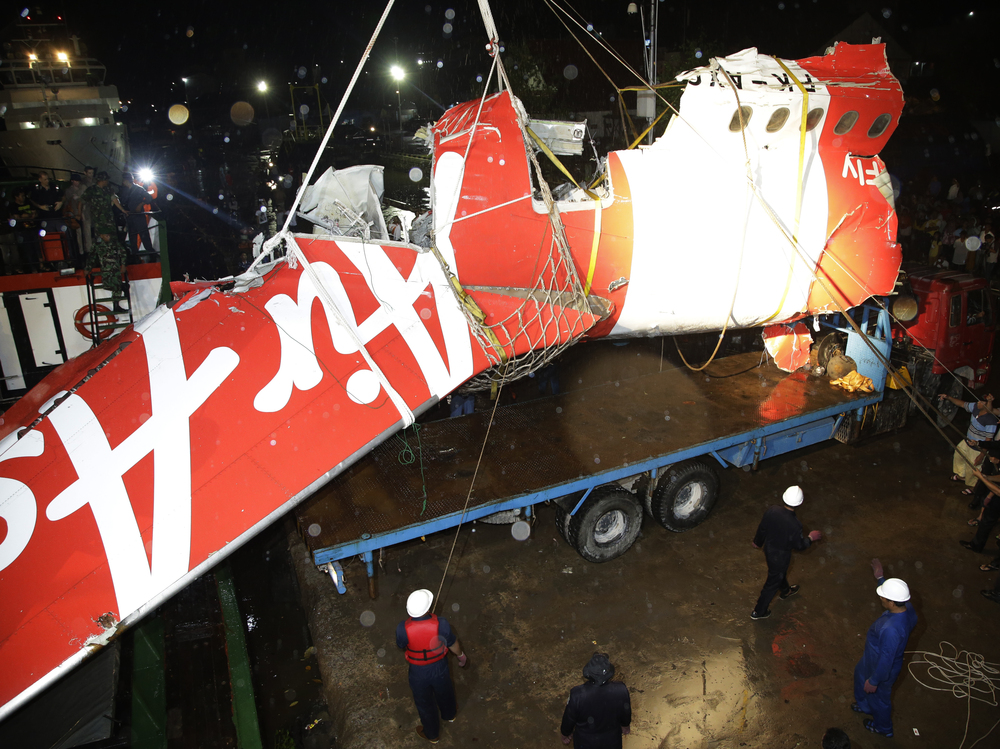 Crew members of Crest Onyx ship and Members of National Search And Rescue Agency unload the wreckage of part of the ill-fated AirAsia Flight 8501 on Sunday. Achmad Ibrahim/AP
