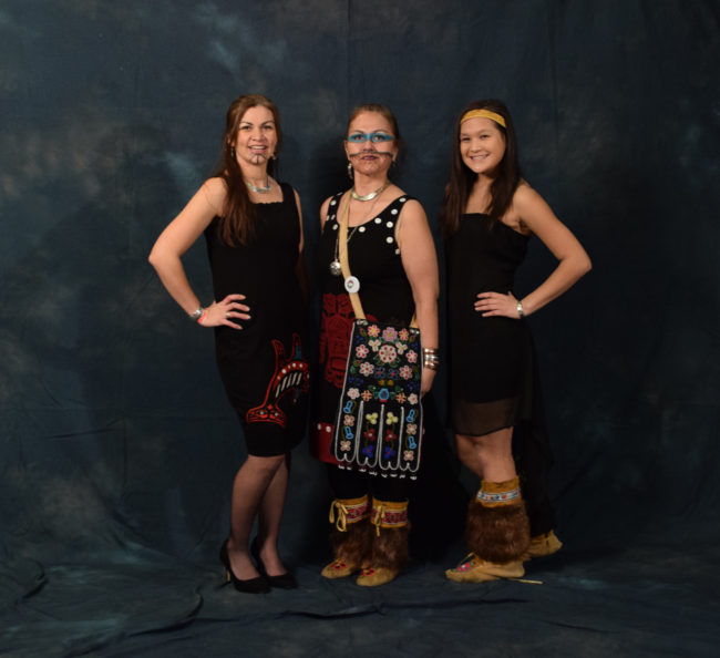 Rhonda Butler, Ann Chilton and Nancy Barnes are all part of the Yees Ku Oo dance group, which escorted Gov. Bill Walker and Lt. Gov. Byron Mallott into the gala. Butler's dress, which she made, is adorned with her clan crest - double fin killer whale. Chilton wore a traditional regalia octopus bag and a dress made by Butler. Nancy wore her aunt's moccasins and a headband bought at AFN. All three are wearing "Chilton bling," jewelry made by Chilton brothers Gene, Brian and Doug. (Photo by Skip Gray/KTOO)
