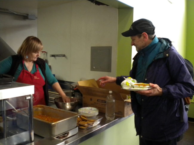 Glory Hole staffer Mindy Lee serves the first meal at the shelter's headquarters since the building shut down for repairs two months ago. (Photo by Kevin Reagan/KTOO)