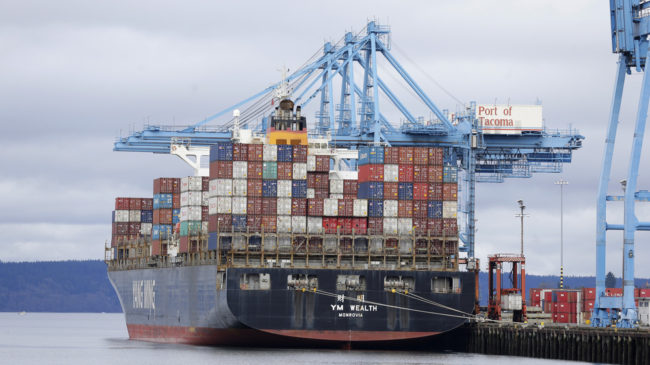 A cargo container ship operated by Yang Ming Marine Transport Corp. sits docked Friday at the Port of Tacoma. Negotiators for the two sides in the labor dispute that has snarled international trade at U.S. West Coast seaports reached a settlement late Friday. Ted S. Warren/AP