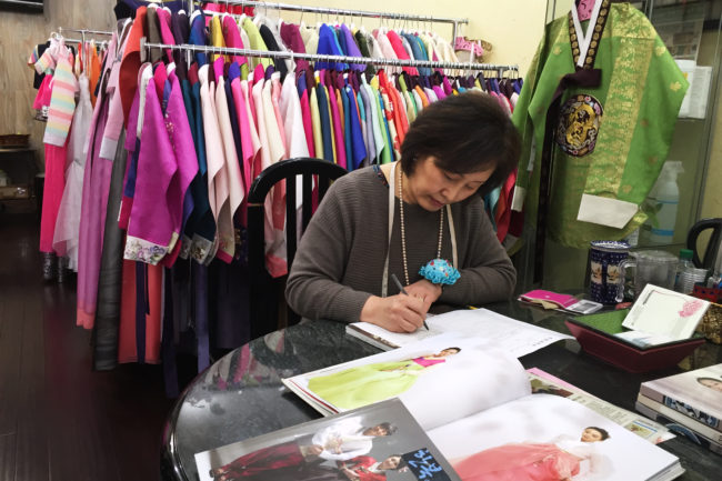 Youjung Jung takes a customer's order for a new outfit at her store Hanbok Story in Queens, N.Y. (Photo by Hansi Lo Wang/NPR)