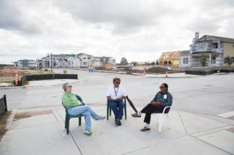 Kathy Van Sluyters (left), Barbara Carr and Colleen Dickinson chat on a recently finished sidewalk across from Wildflower Terrace, a mixed-income apartment building in the Mueller development for people ages 55 and over. (Julia Robinson for NPR)
